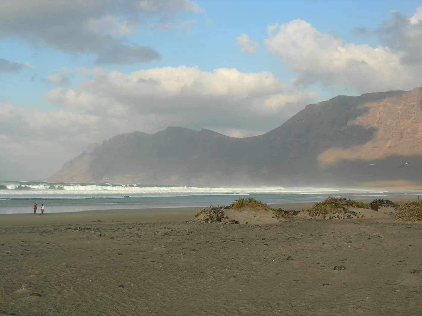 The wide beach at Famara, with surf rolling in below the long wall of the Famara cliffs.