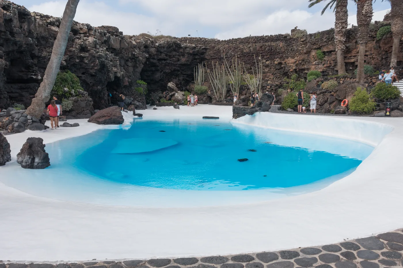 The white-edged turquoise pool among palms and volcanic rock in the Jameo Grande.
