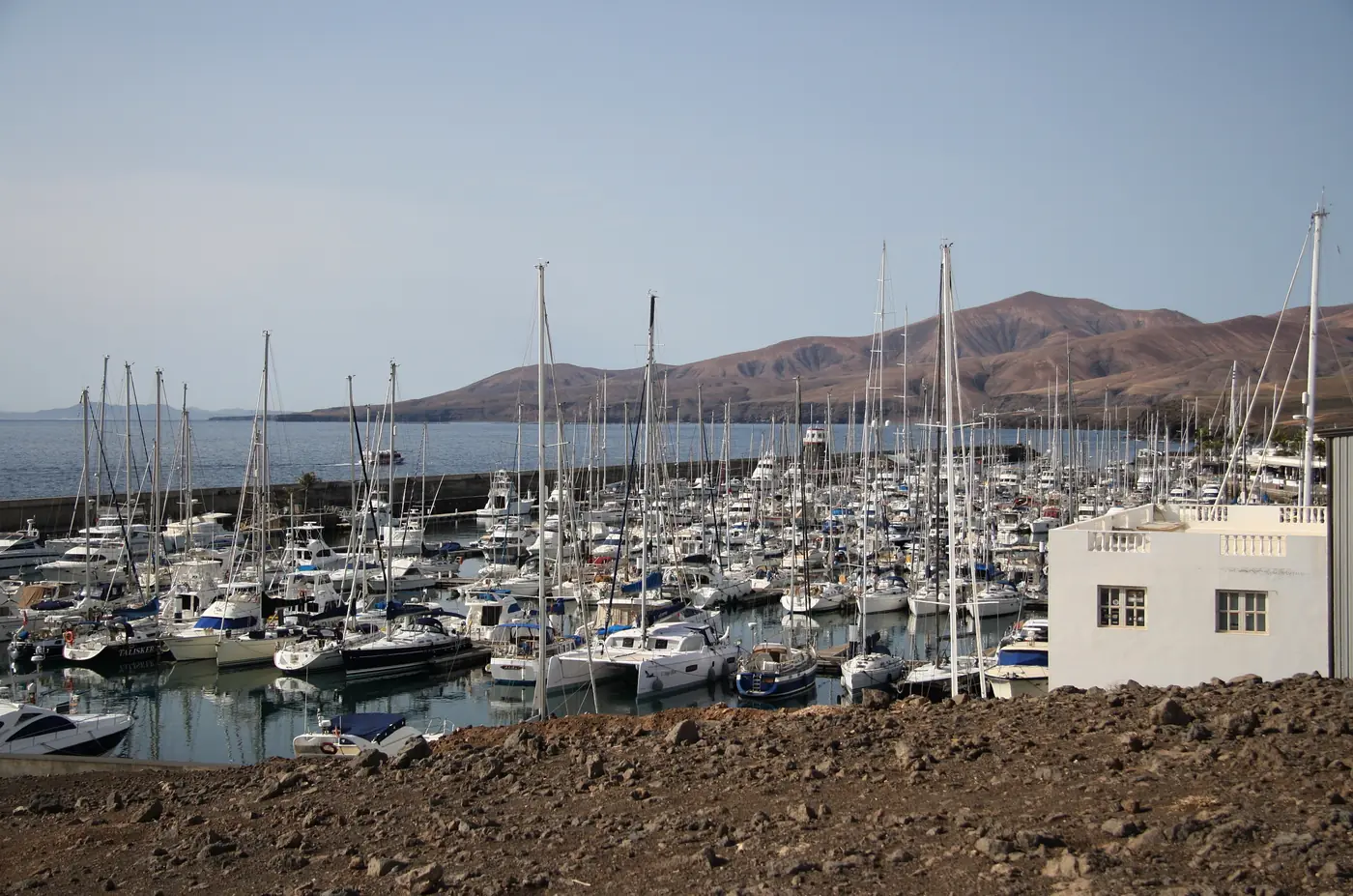 Yachts packed into the marina at Puerto Calero, with brown volcanic hills behind.