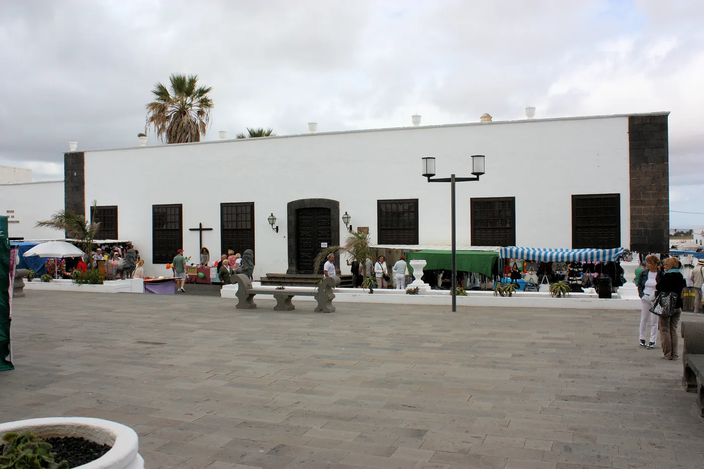 The white façade of the Palacio Spínola on a square in Teguise, with market stalls beside it.