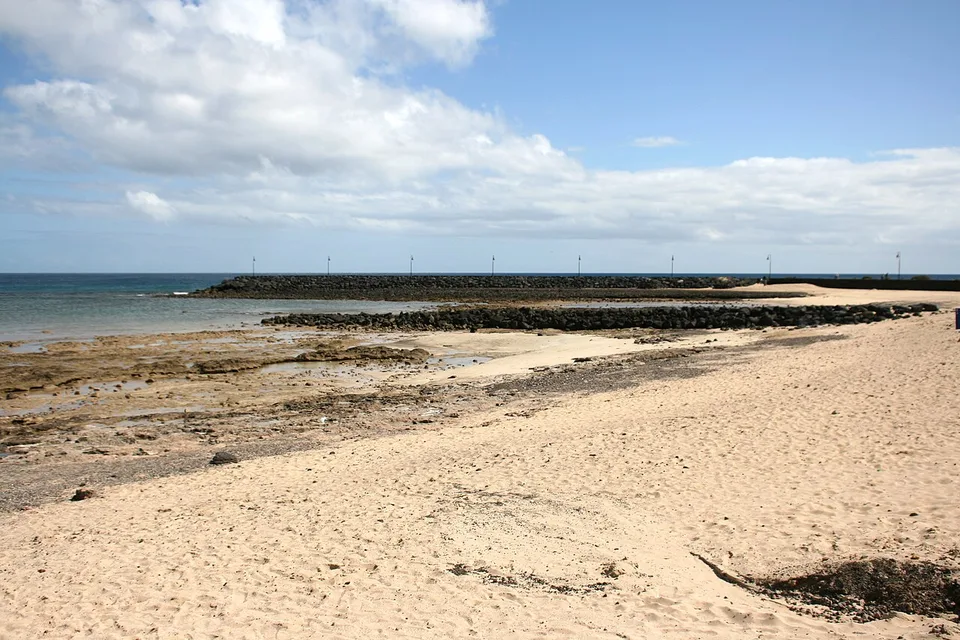 Pale sand, volcanic rock and sheltered water at Playa de los Charcos in Costa Teguise.